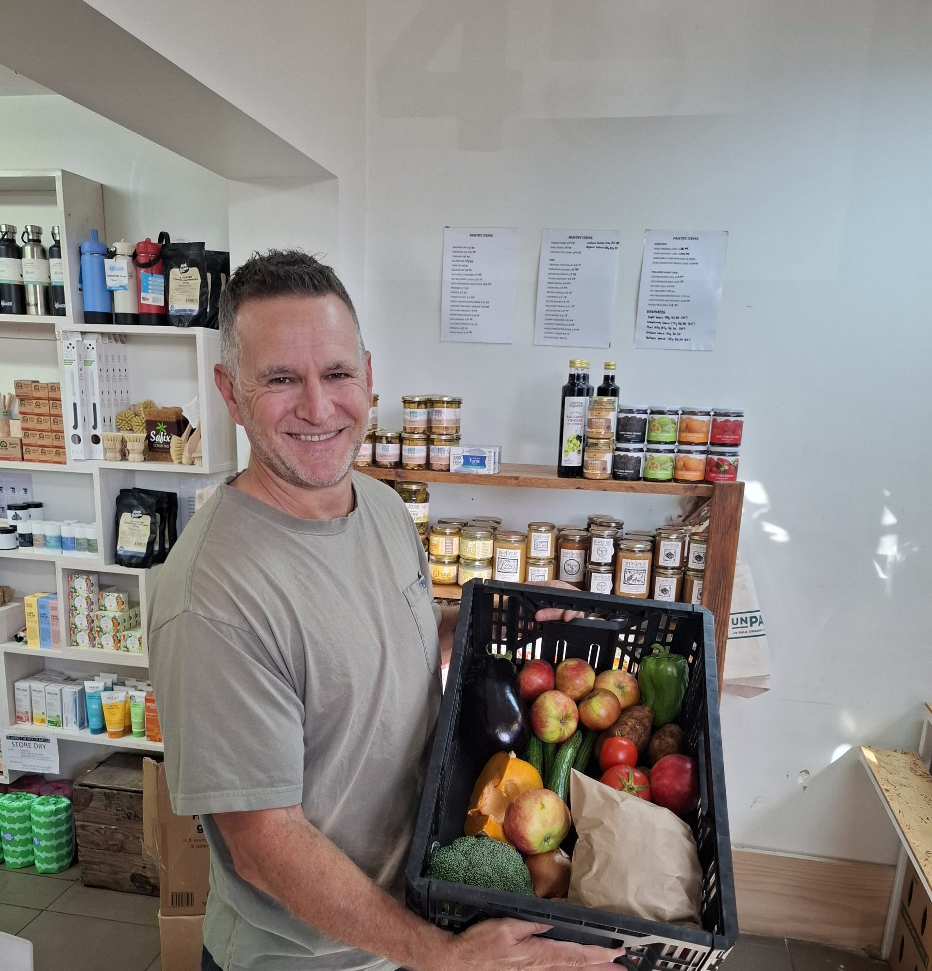 Josh from Unpacked Wholefoods holds a crate full of fruit and vegetables
