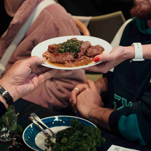 Two hands hold a plate of food.