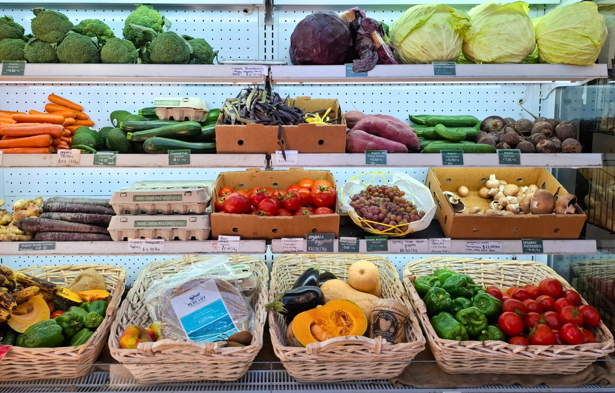 Baskets of various fruits and vegetable in an open shelved fridge