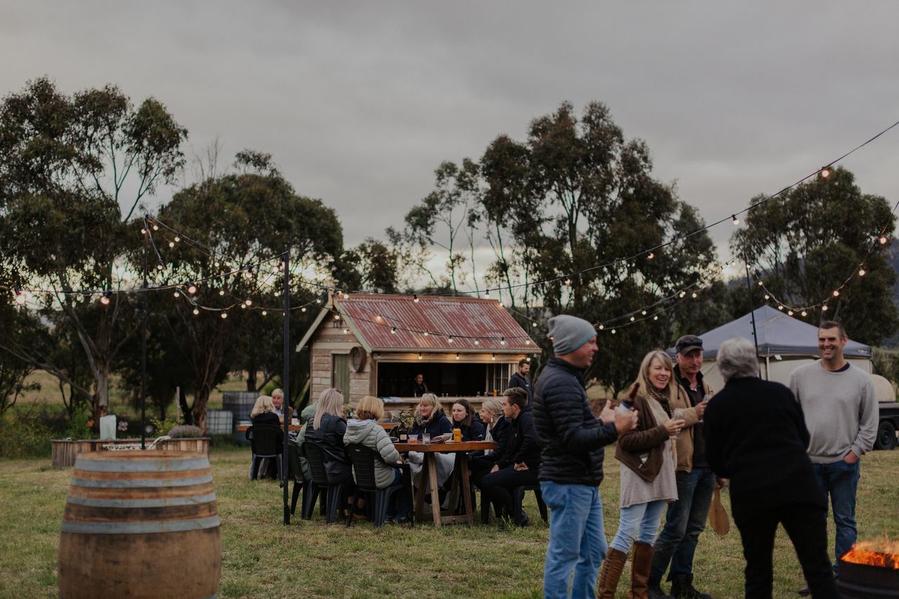A group gathers by the fire at Killara Distillery with winter jackets and hats