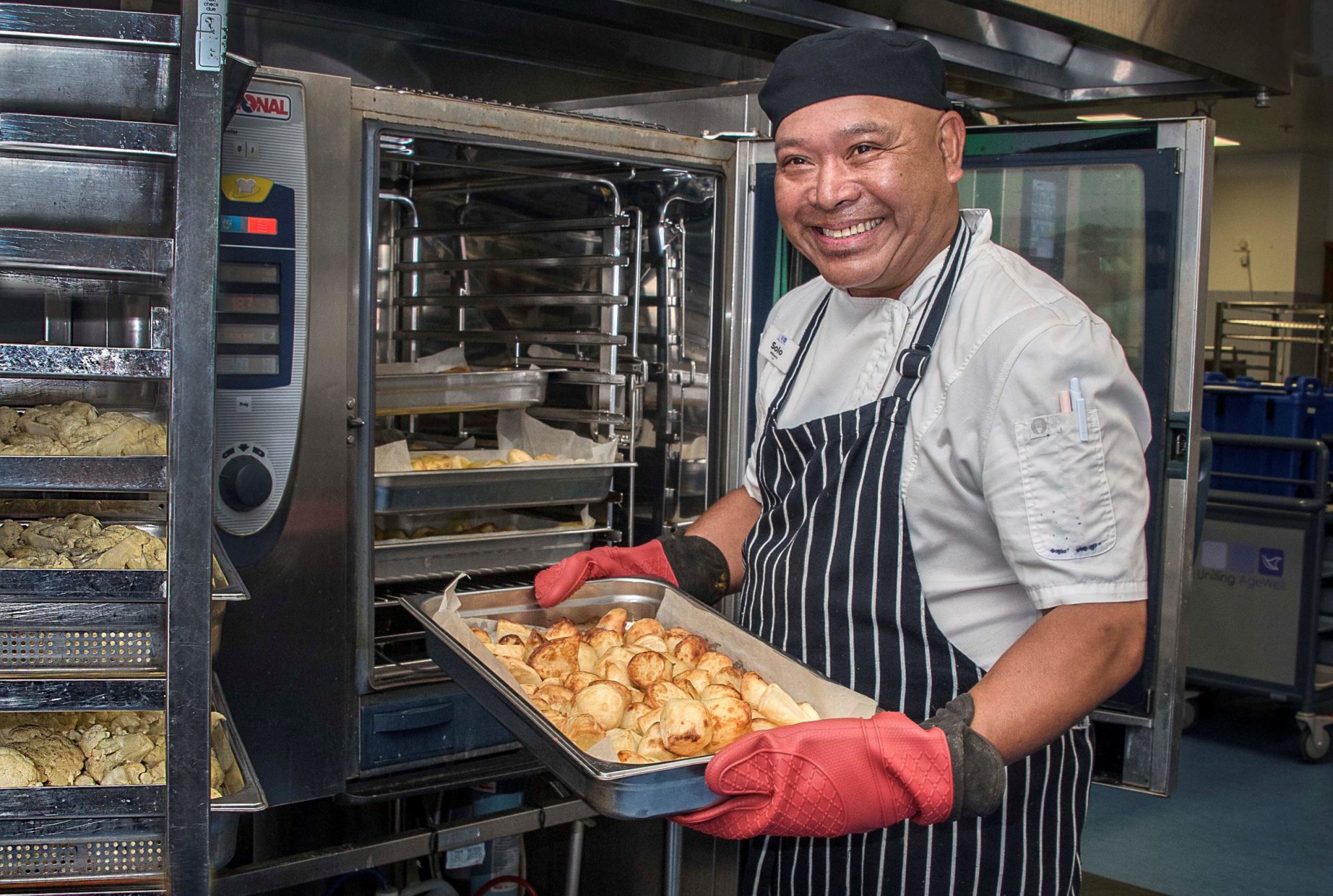 Meals on Wheels Chef holding a tray of cooked goods