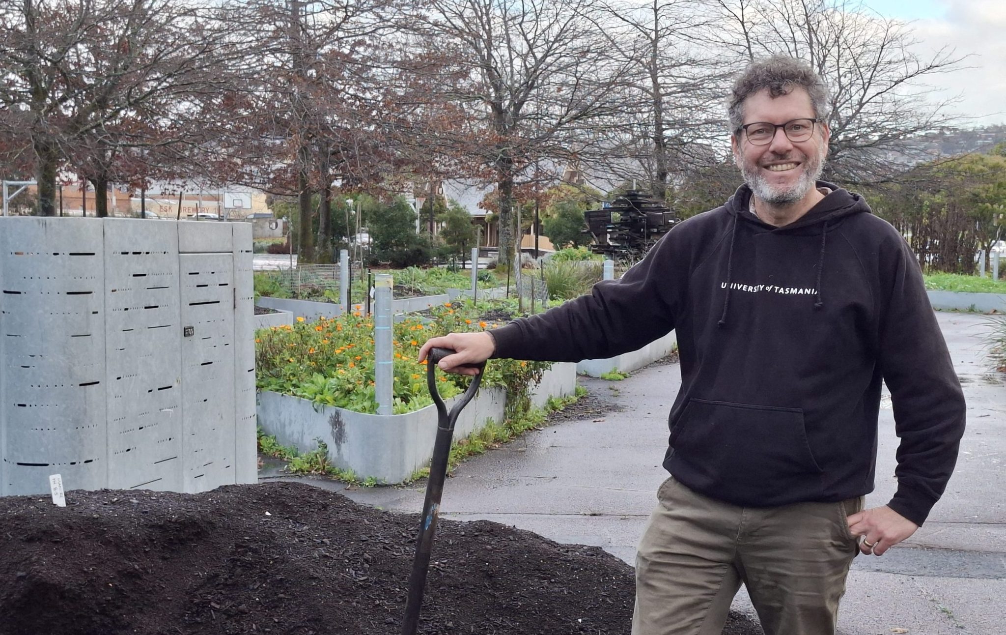 A man stands at a mound of compost with a pitch fork