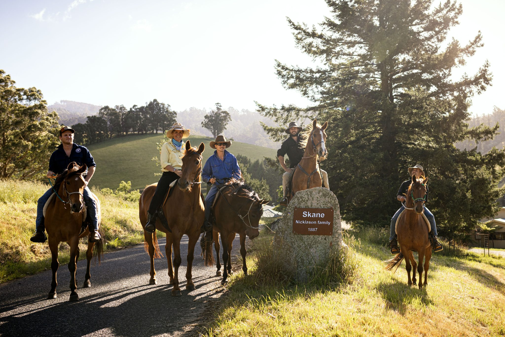 4 riders on horses stand together with a sign that reads 
